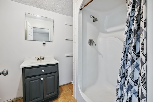 bathroom with tile patterned floors, vanity, walk in shower, and a textured ceiling