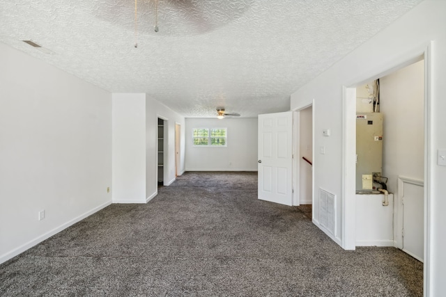 unfurnished room with dark carpet, water heater, and a textured ceiling