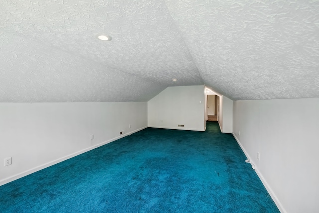 bonus room featuring a textured ceiling, lofted ceiling, and dark colored carpet