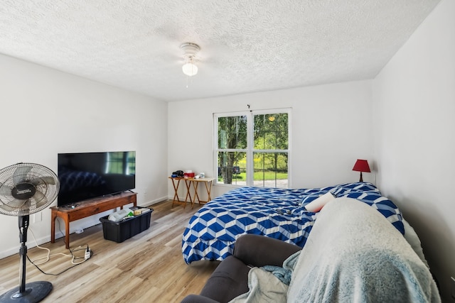 bedroom with ceiling fan, hardwood / wood-style flooring, and a textured ceiling