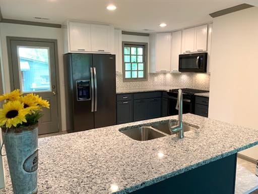 kitchen with white cabinetry, a healthy amount of sunlight, black appliances, and decorative backsplash