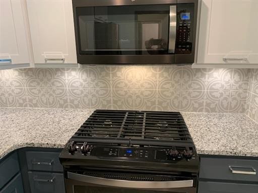 interior details with light stone countertops, decorative backsplash, white cabinetry, and stainless steel appliances