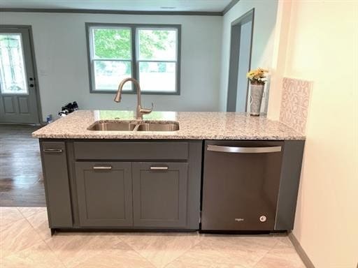 kitchen featuring stainless steel dishwasher, sink, light stone counters, and a healthy amount of sunlight