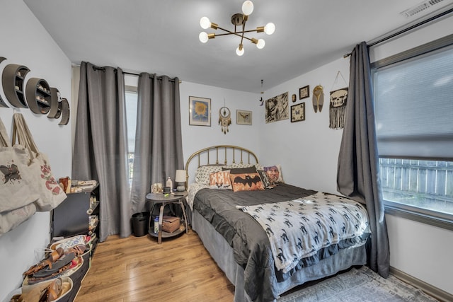 bedroom featuring light hardwood / wood-style floors, multiple windows, and an inviting chandelier