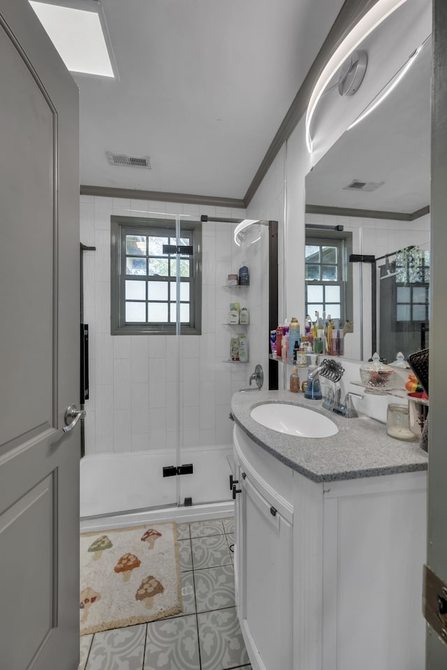 bathroom featuring vanity, crown molding, a shower with shower door, and tile patterned flooring