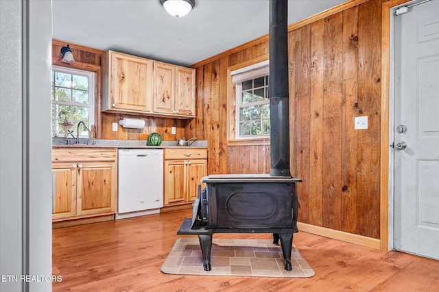 kitchen featuring dishwasher, wood walls, light hardwood / wood-style flooring, and a wood stove