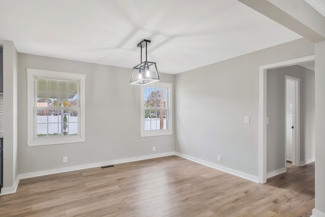 unfurnished dining area with a notable chandelier and light hardwood / wood-style flooring