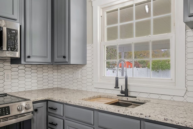 kitchen with decorative backsplash, gray cabinets, sink, and stainless steel appliances