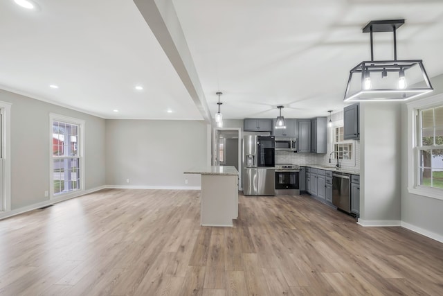 kitchen with gray cabinetry, pendant lighting, sink, light wood-type flooring, and appliances with stainless steel finishes