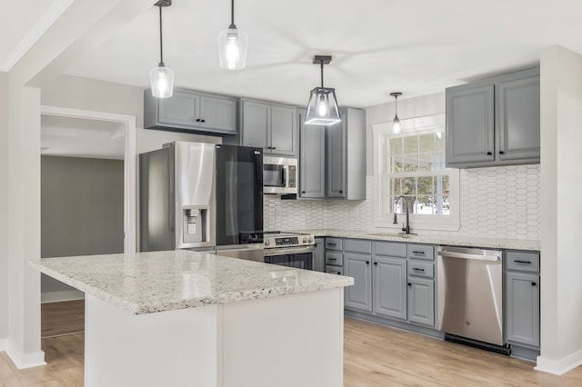 kitchen with pendant lighting, light hardwood / wood-style floors, appliances with stainless steel finishes, and tasteful backsplash