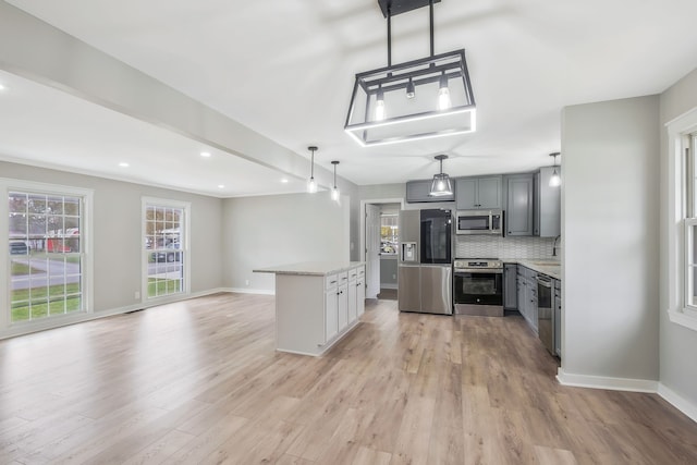 kitchen featuring decorative light fixtures, stainless steel appliances, gray cabinetry, and light hardwood / wood-style floors