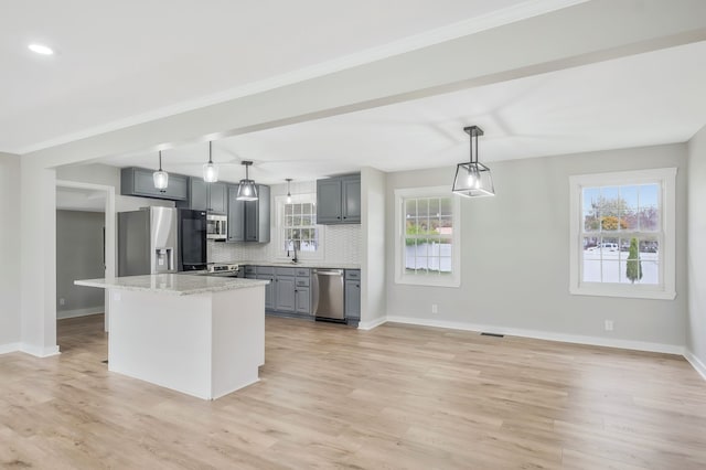 kitchen featuring light wood-type flooring, tasteful backsplash, stainless steel appliances, pendant lighting, and gray cabinets