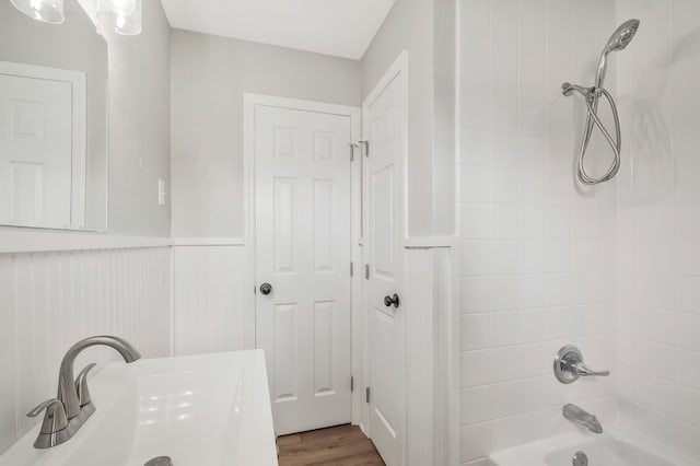 bathroom featuring hardwood / wood-style floors, tiled shower / bath combo, and sink