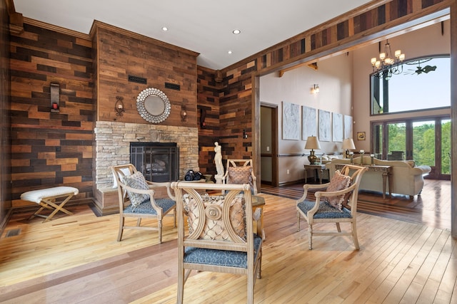 living room featuring light hardwood / wood-style flooring, wooden walls, a fireplace, and a high ceiling