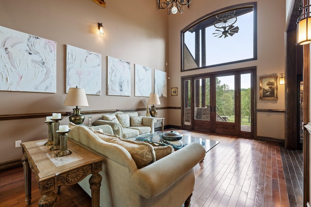 living room with a towering ceiling, french doors, and hardwood / wood-style flooring