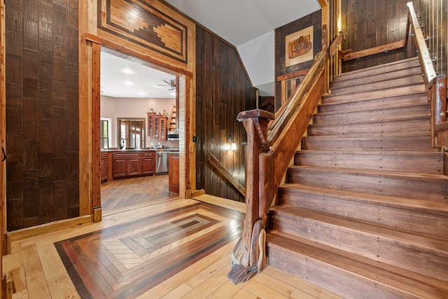 stairway featuring ceiling fan, hardwood / wood-style flooring, and wooden walls