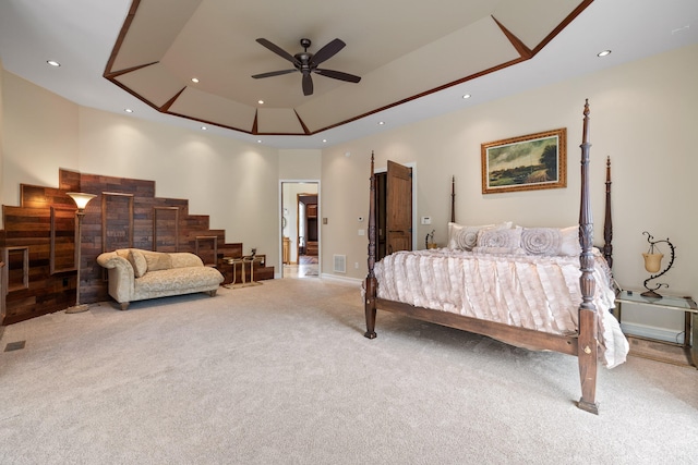 carpeted bedroom with ceiling fan and a raised ceiling