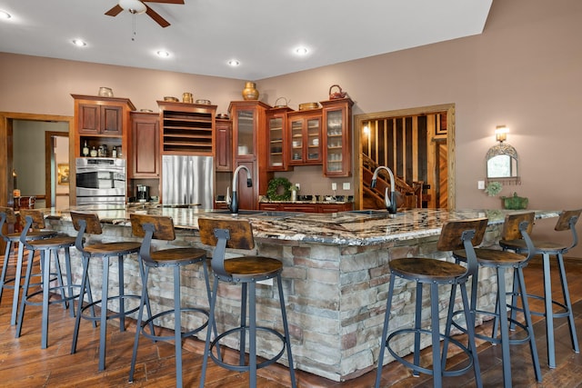 kitchen with sink, ceiling fan, dark hardwood / wood-style floors, and a breakfast bar