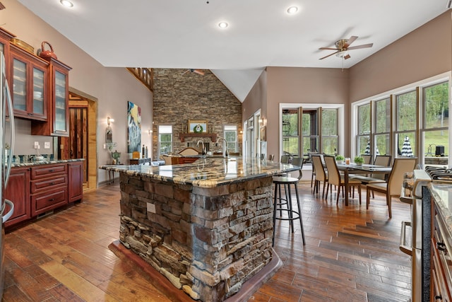 kitchen featuring dark stone countertops, stainless steel range oven, dark hardwood / wood-style floors, and ceiling fan