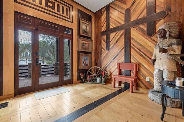 foyer featuring french doors, wooden walls, and light wood-type flooring