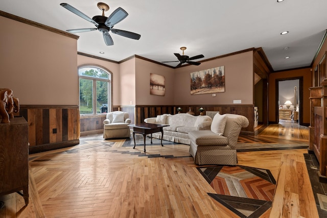 living room featuring ornamental molding, wooden walls, light parquet floors, and ceiling fan