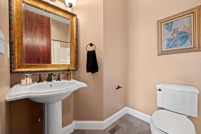 bathroom with toilet, sink, and tile patterned flooring