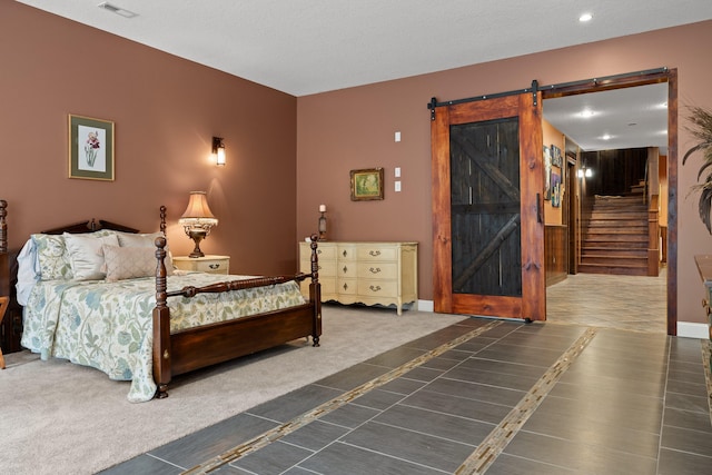 bedroom featuring dark colored carpet, a textured ceiling, and a barn door