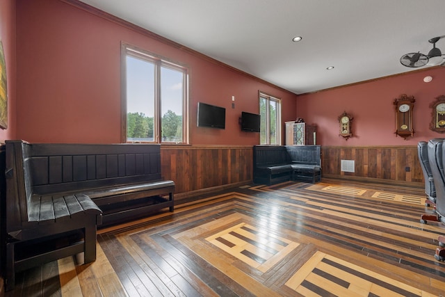 interior space featuring hardwood / wood-style flooring, ornamental molding, and wood walls