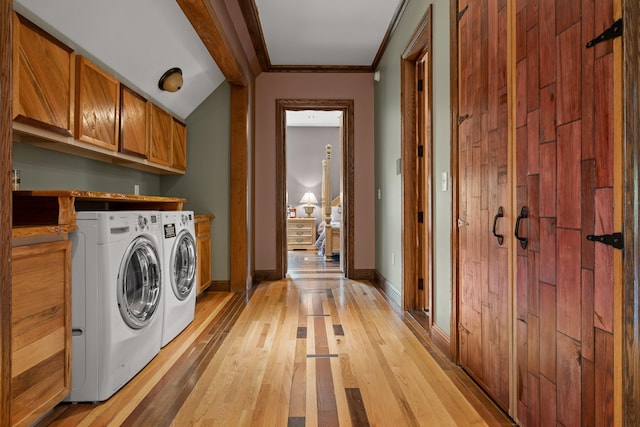 clothes washing area with cabinets, light hardwood / wood-style flooring, ornamental molding, and washer and clothes dryer