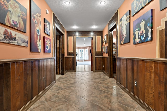 corridor featuring wood walls and a textured ceiling