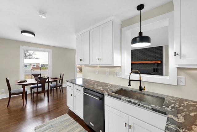 kitchen with white cabinetry, sink, stainless steel dishwasher, and dark stone counters