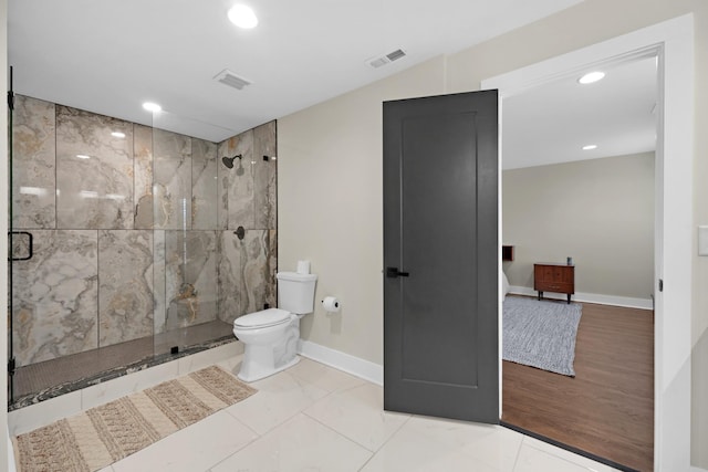 bathroom featuring a shower with door and toilet