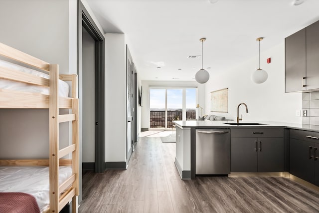 kitchen featuring stainless steel dishwasher, dark hardwood / wood-style floors, sink, kitchen peninsula, and pendant lighting