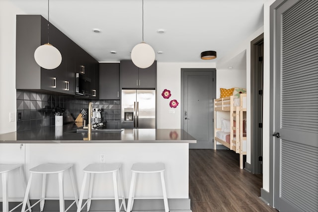 kitchen with pendant lighting, kitchen peninsula, stainless steel fridge with ice dispenser, a breakfast bar, and dark hardwood / wood-style flooring