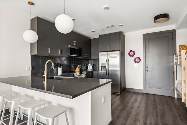 kitchen featuring stainless steel appliances, kitchen peninsula, decorative light fixtures, and a breakfast bar