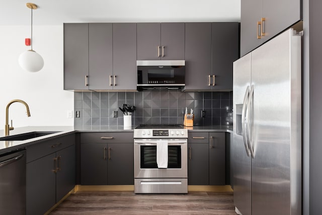 kitchen featuring stainless steel appliances, decorative light fixtures, sink, and gray cabinetry