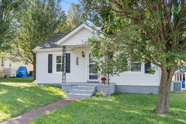 view of front of home with a front yard and central AC