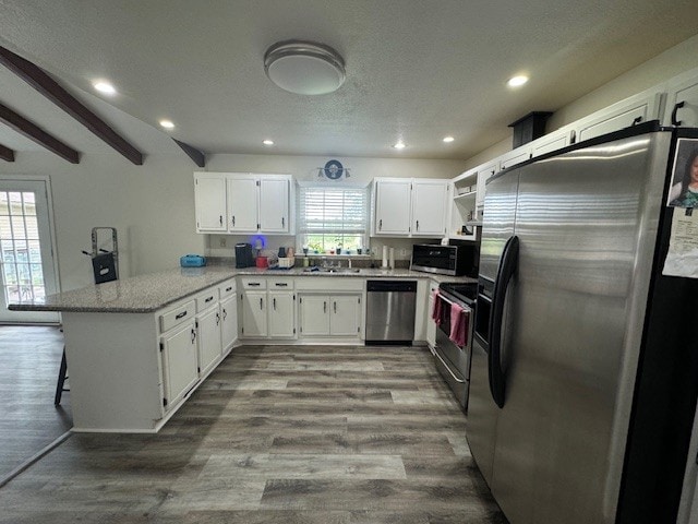 kitchen featuring a wealth of natural light, appliances with stainless steel finishes, kitchen peninsula, and white cabinetry