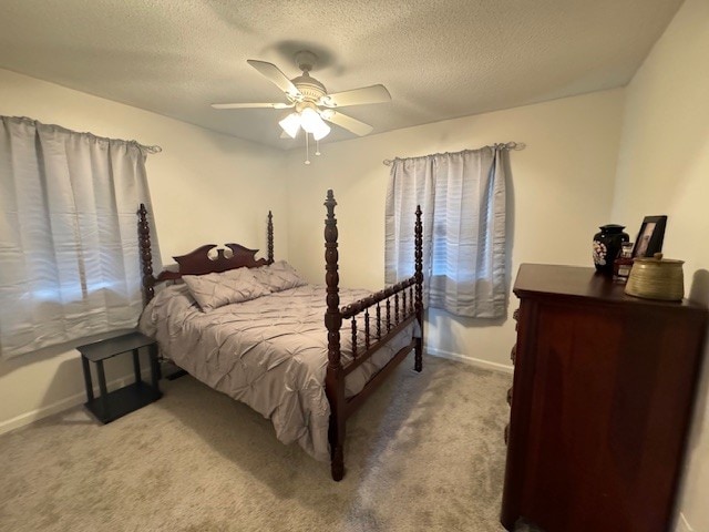 carpeted bedroom featuring ceiling fan and a textured ceiling