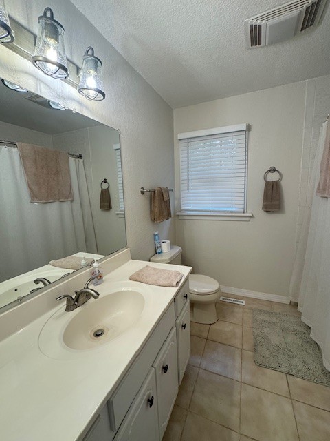 bathroom featuring vanity, a textured ceiling, tile patterned floors, toilet, and a shower with shower curtain