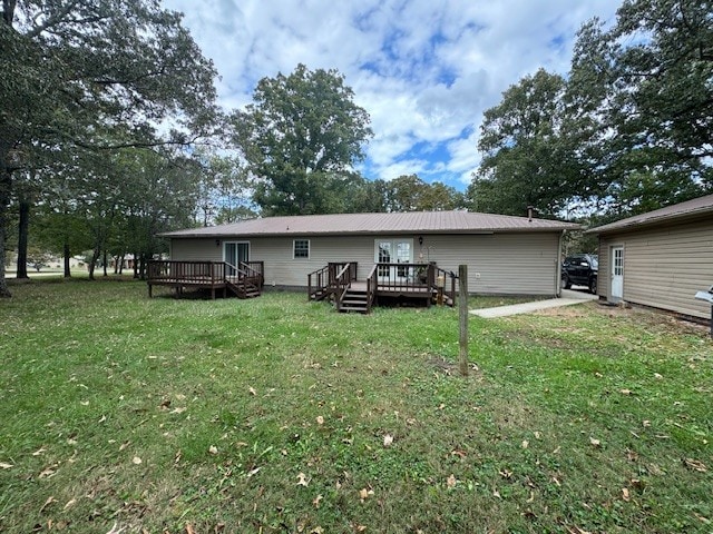 back of property with a wooden deck and a lawn