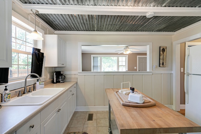 kitchen featuring white cabinets, white refrigerator, pendant lighting, light tile patterned flooring, and sink