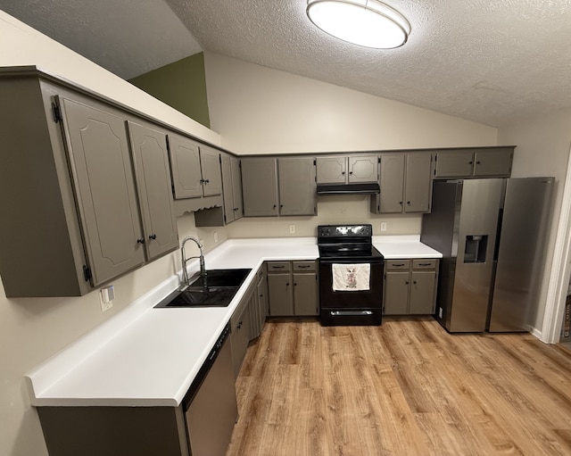 kitchen with gray cabinets, appliances with stainless steel finishes, sink, and vaulted ceiling