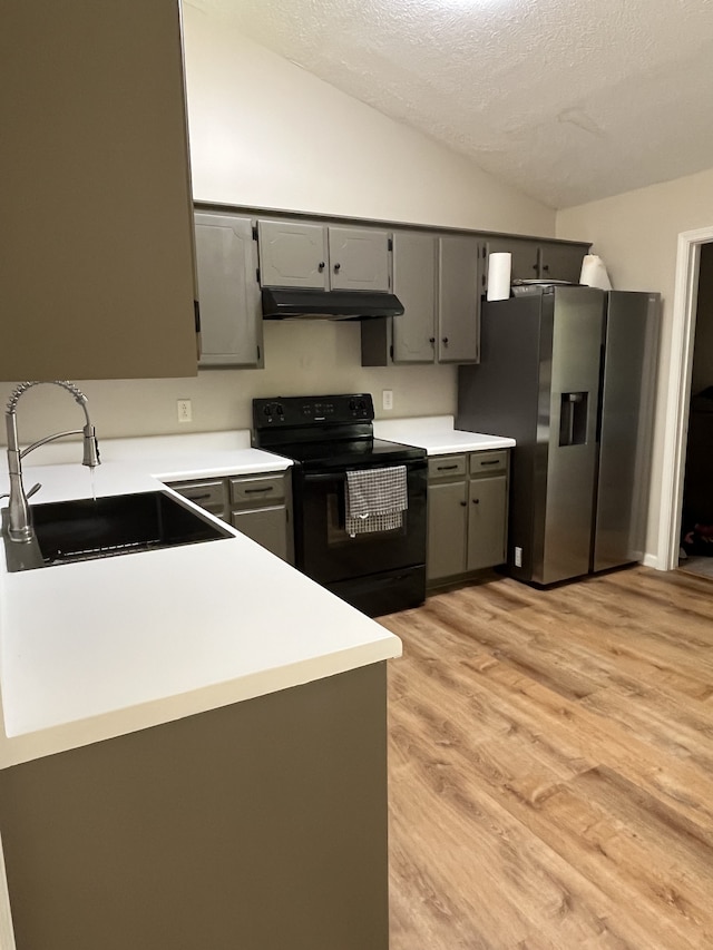 kitchen with lofted ceiling, stainless steel refrigerator with ice dispenser, sink, gray cabinetry, and black electric range oven