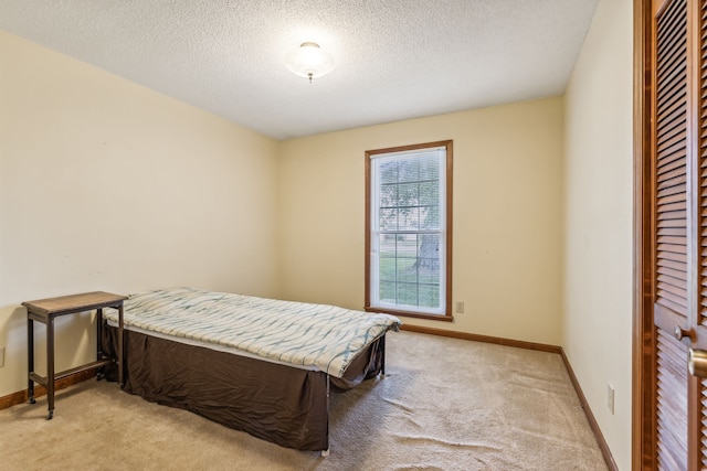 bedroom featuring light colored carpet and a textured ceiling