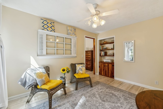 living area featuring ceiling fan, built in features, and hardwood / wood-style floors