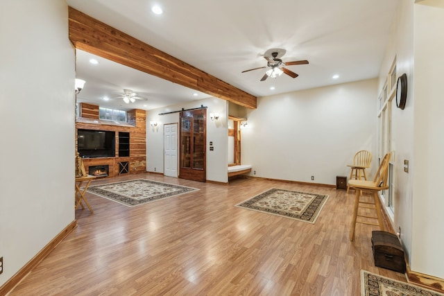 living room with ceiling fan, light hardwood / wood-style flooring, and a barn door