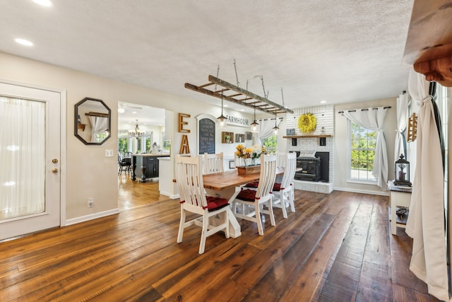 dining area with a textured ceiling, a fireplace, and dark hardwood / wood-style flooring