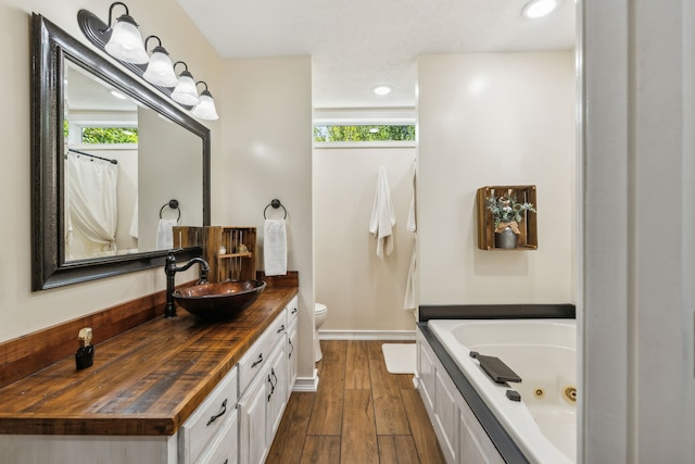 bathroom with hardwood / wood-style flooring, toilet, a bath, and a wealth of natural light