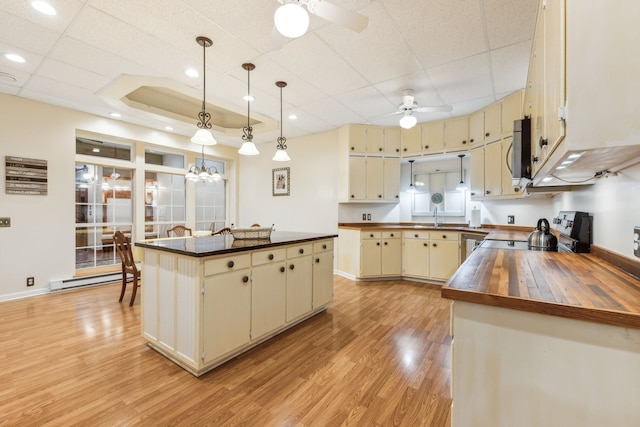 kitchen with cream cabinets, pendant lighting, ceiling fan with notable chandelier, a kitchen island, and electric range